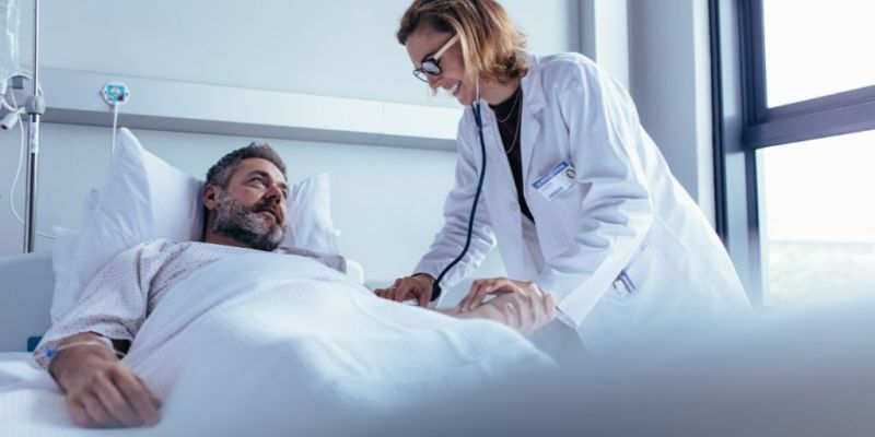 Man laying down in a hospital bed next to a doctor