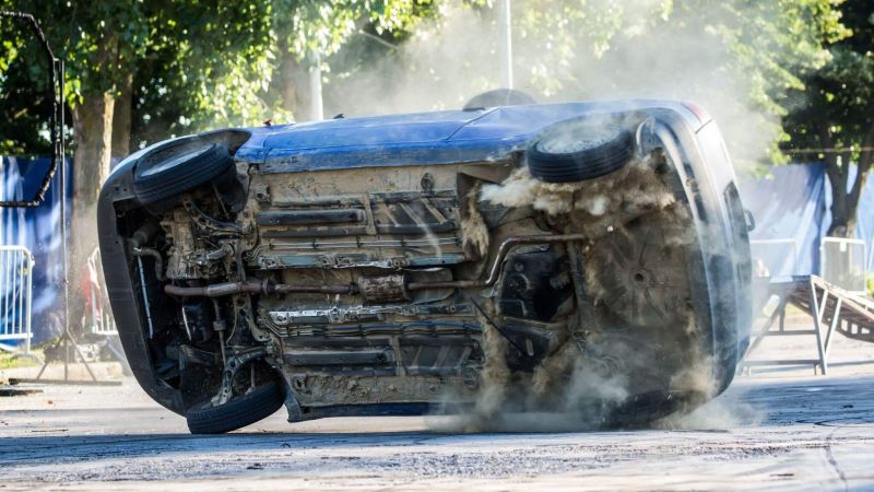 a car that is sitting in the street after a rollover accident and with visible damage