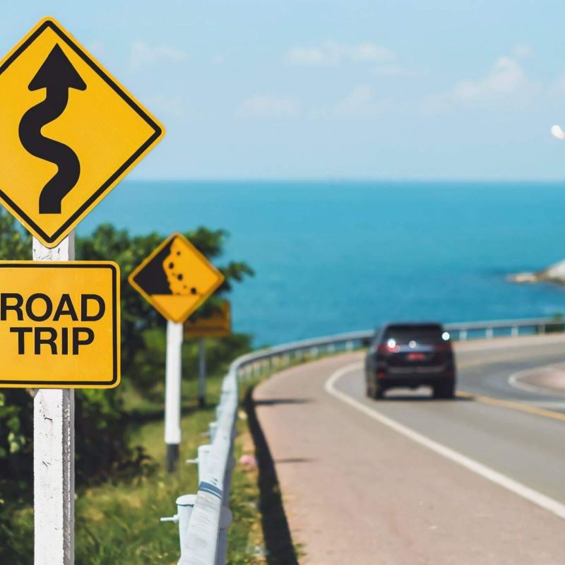 a road sign on the side of a road next to the ocean