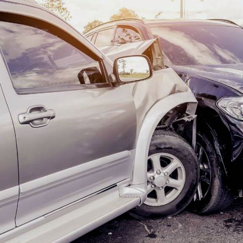 Two cars involved in a traffic accident with visible damage on a sunny day.