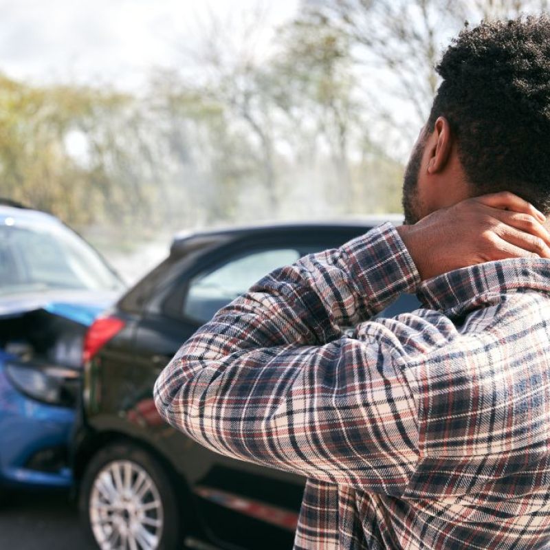 man holding neck looking at car accident
