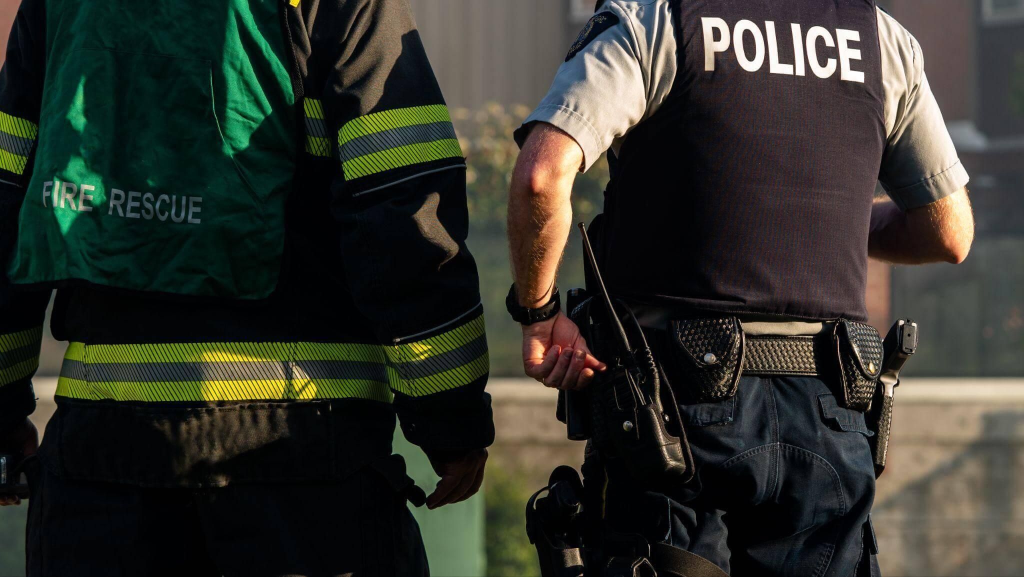 Two first-responders standing next to each other, one is a fireman and the other a police officer
