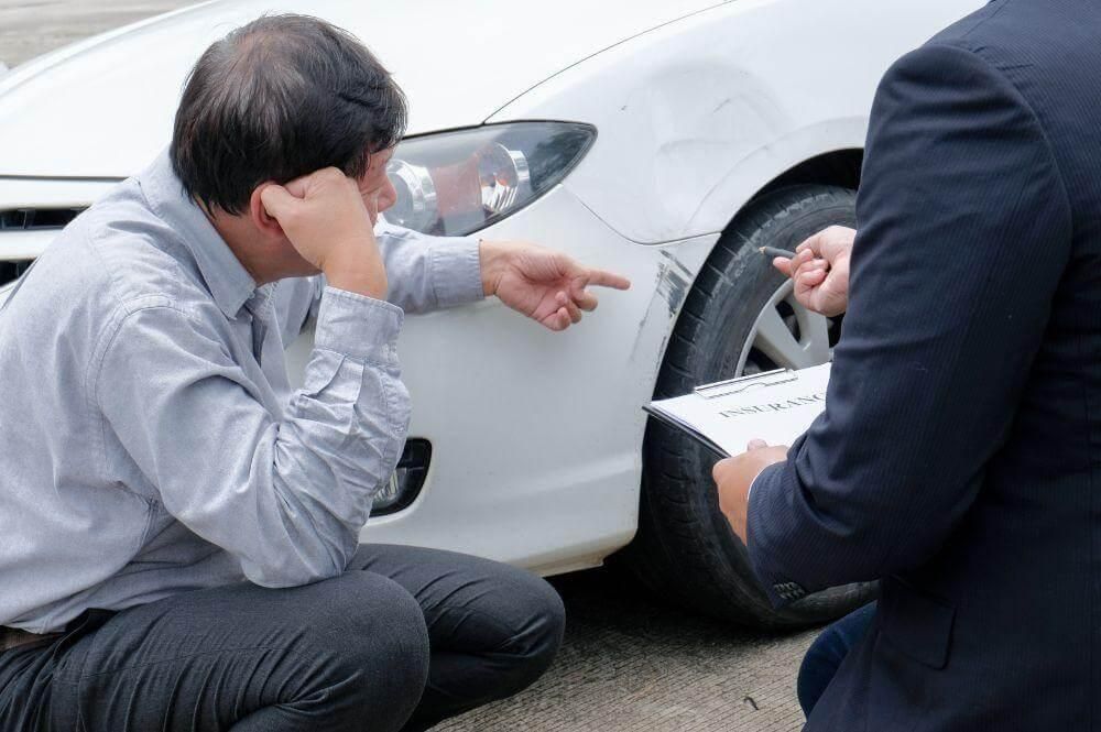 Man sitting by a white car, possibly