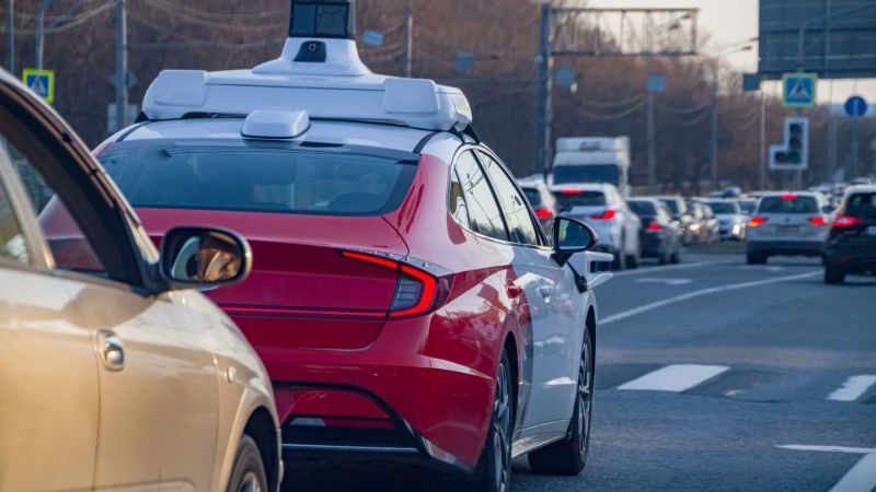 Self-driving red car by traffic light on city street