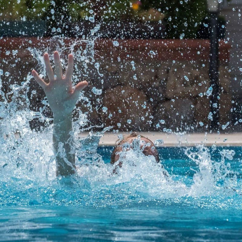 a person splashing water in a swimming pool and that person seems to be drowning