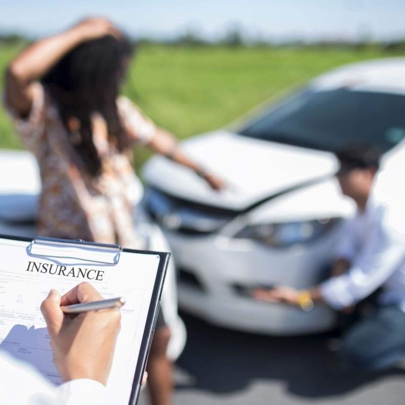 a woman holding a clipboard in front of a car that was involved in an accident