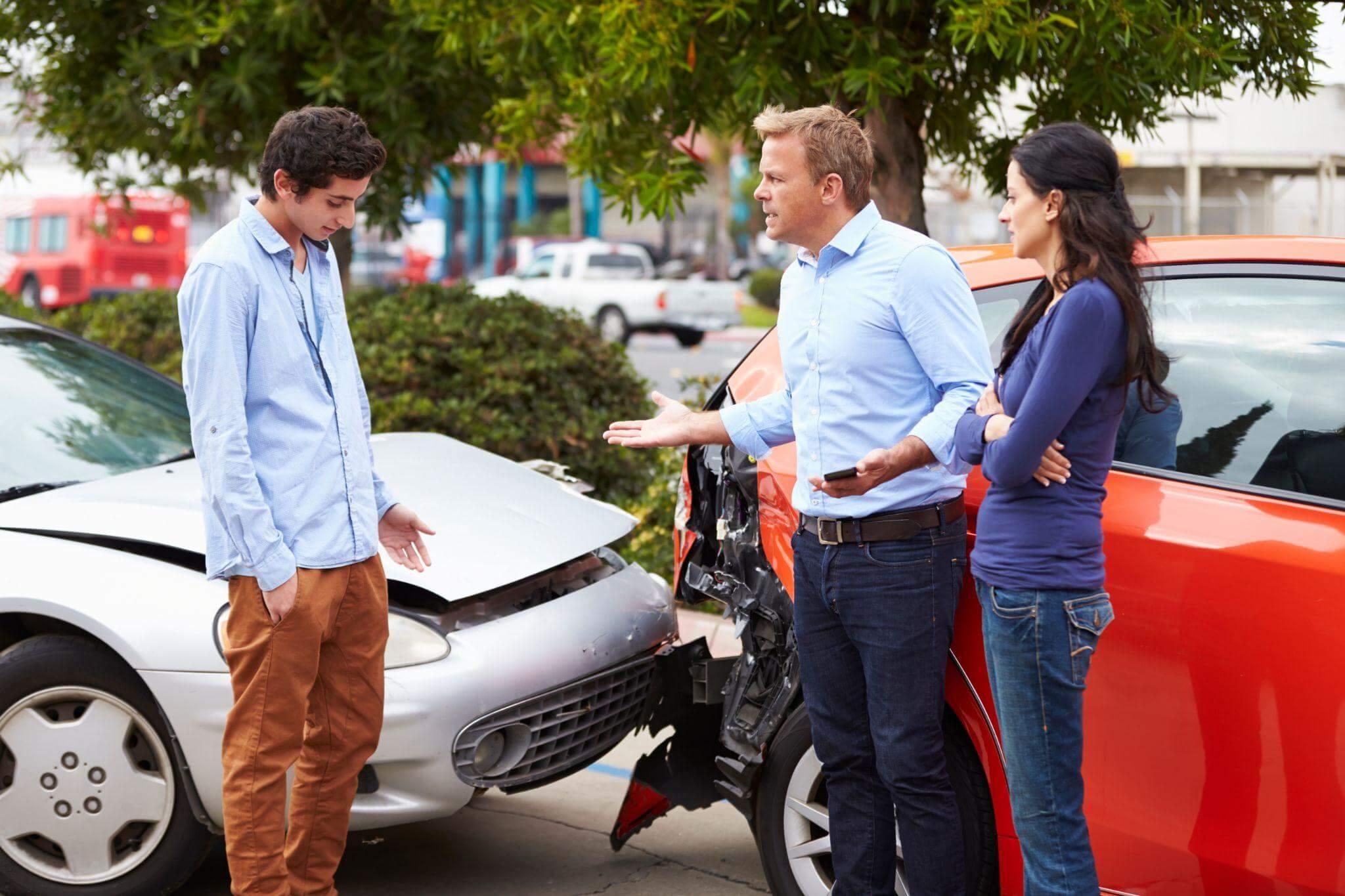 People standing beside a car after an accident
