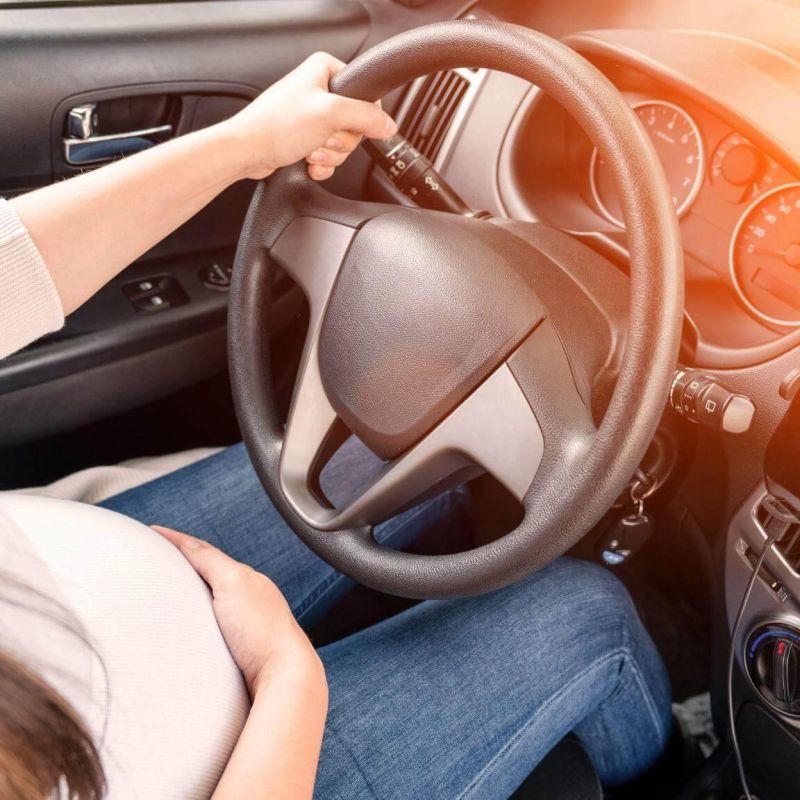 a woman driving a car with her hand on the steering wheel