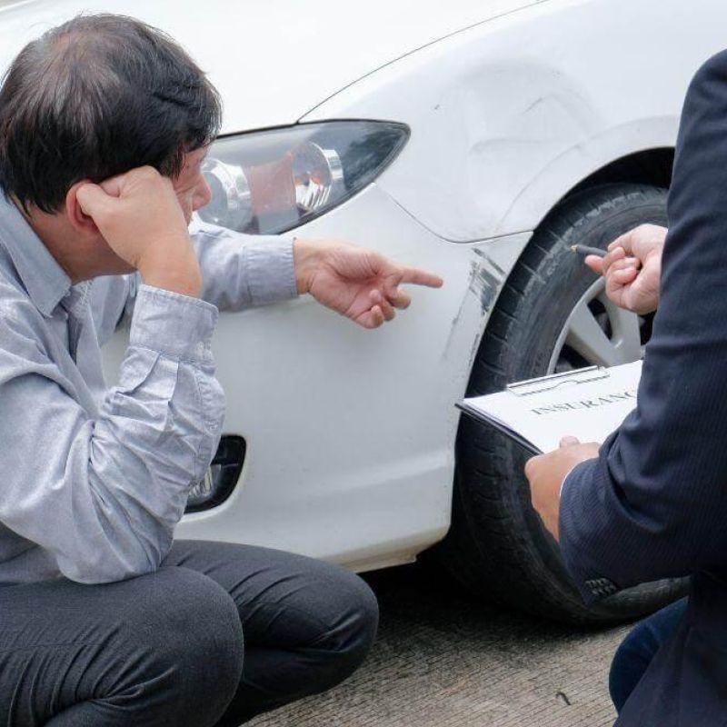 Man sitting by a white car, possibly