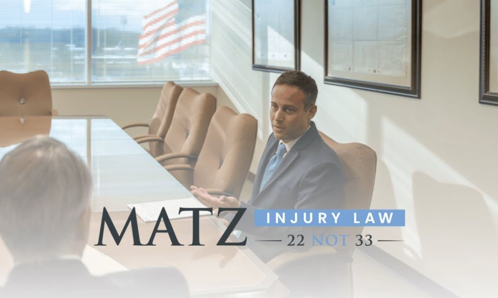 Lawyer in office meeting at Matz Injury Law, discussing legal matters, with window view and company logo displayed.