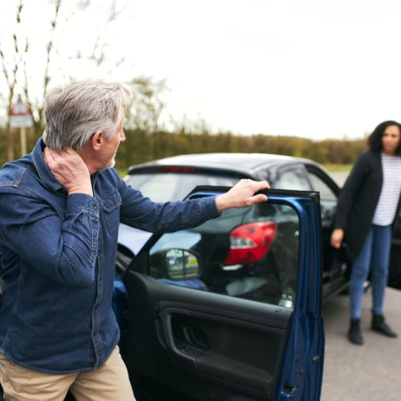 man getting out of a car holding his neck