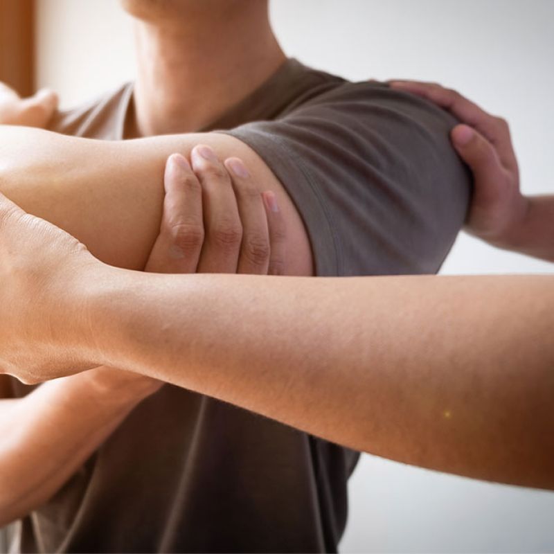 Person receiving physical therapy on shoulder by a therapist.