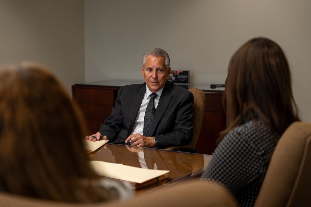 Business meeting with a man in a suit discussing with two people in an office setting.