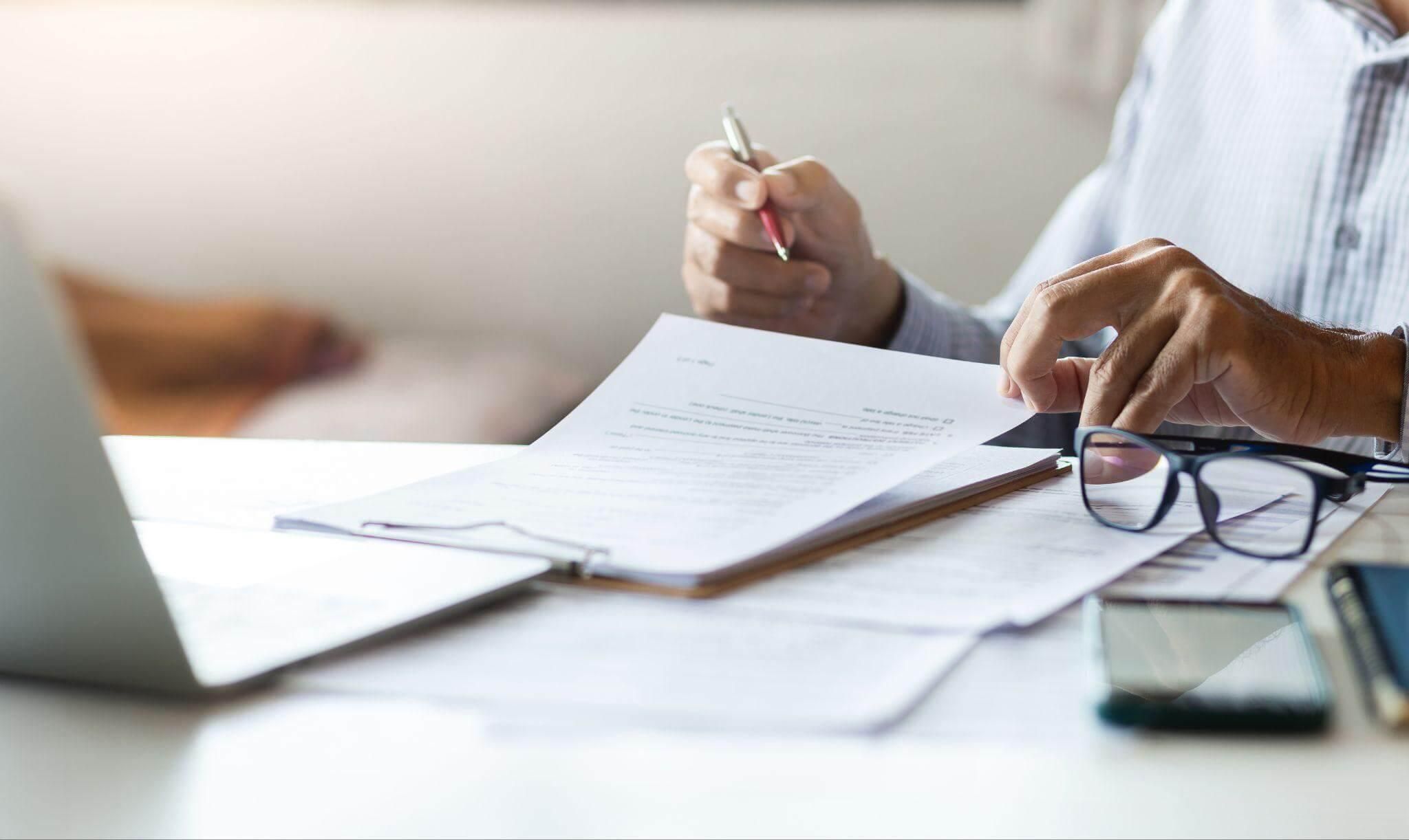 Man writing at desk with pen and paper