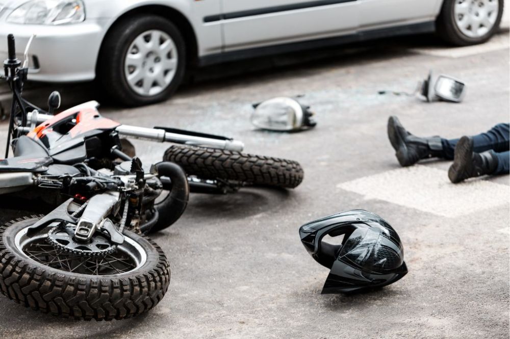 Motorcycle laying in road next to helmet