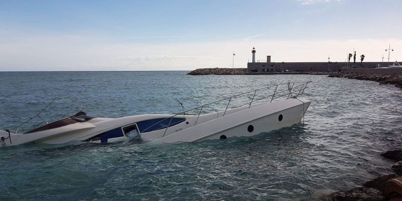 a white boat is in the water near the shore and is slowly sinking