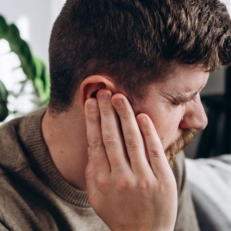 a man is holding his ear, he seems to be in pain