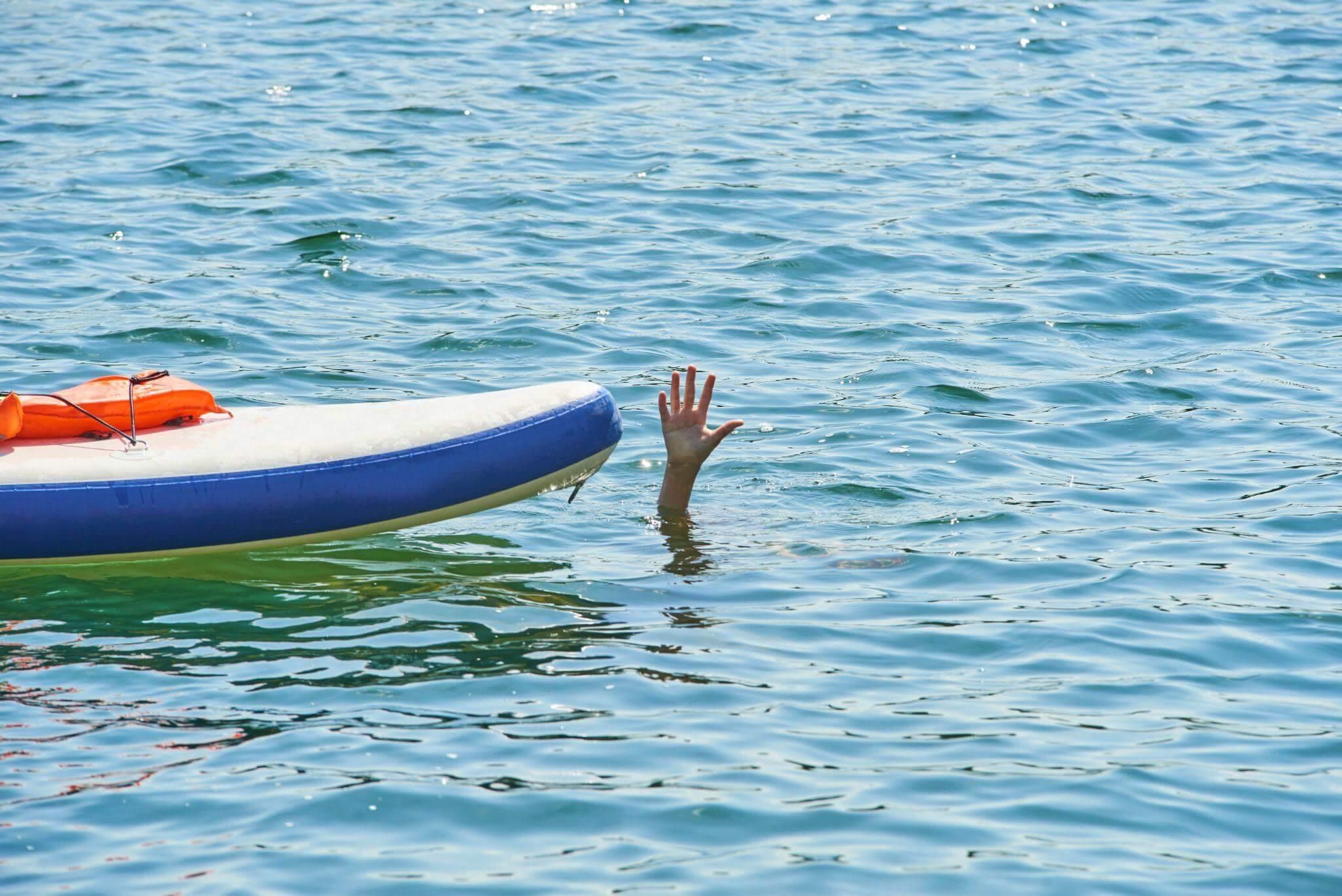 a hand sticking out of the water near a boat