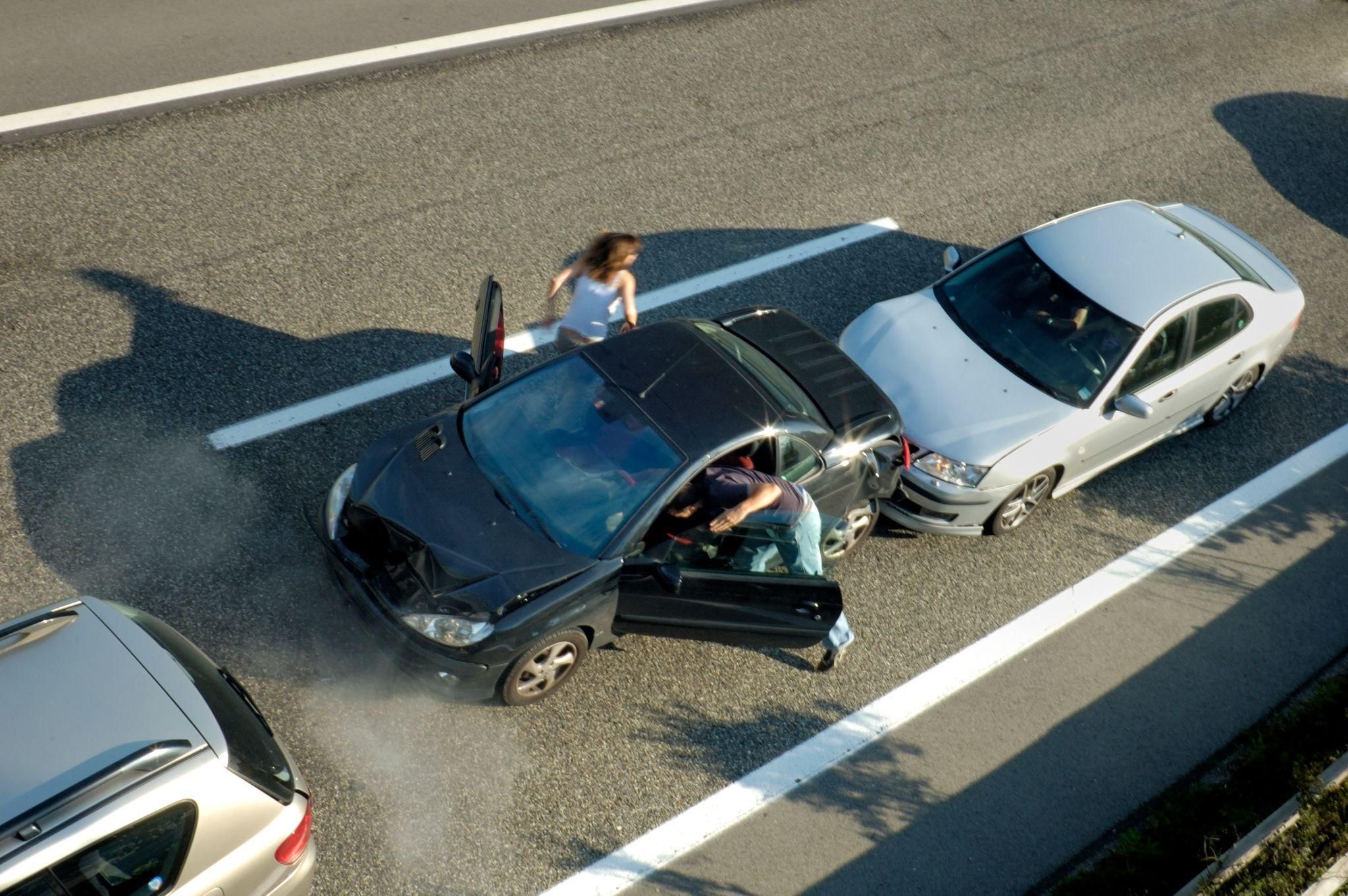 Three-car collision on highway with people exiting vehicles safely.