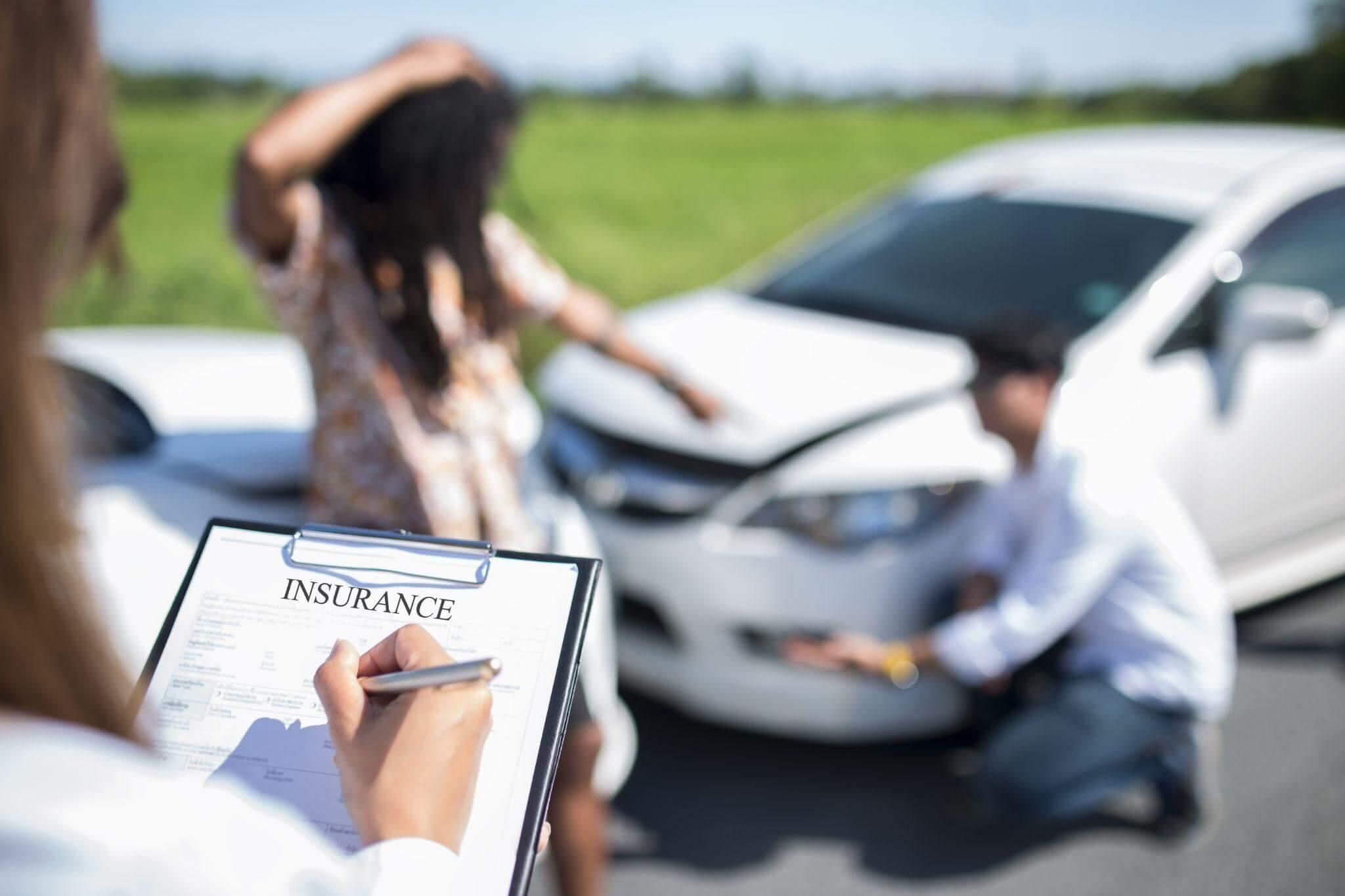a woman holding a clipboard in front of a car that was involved in an accident