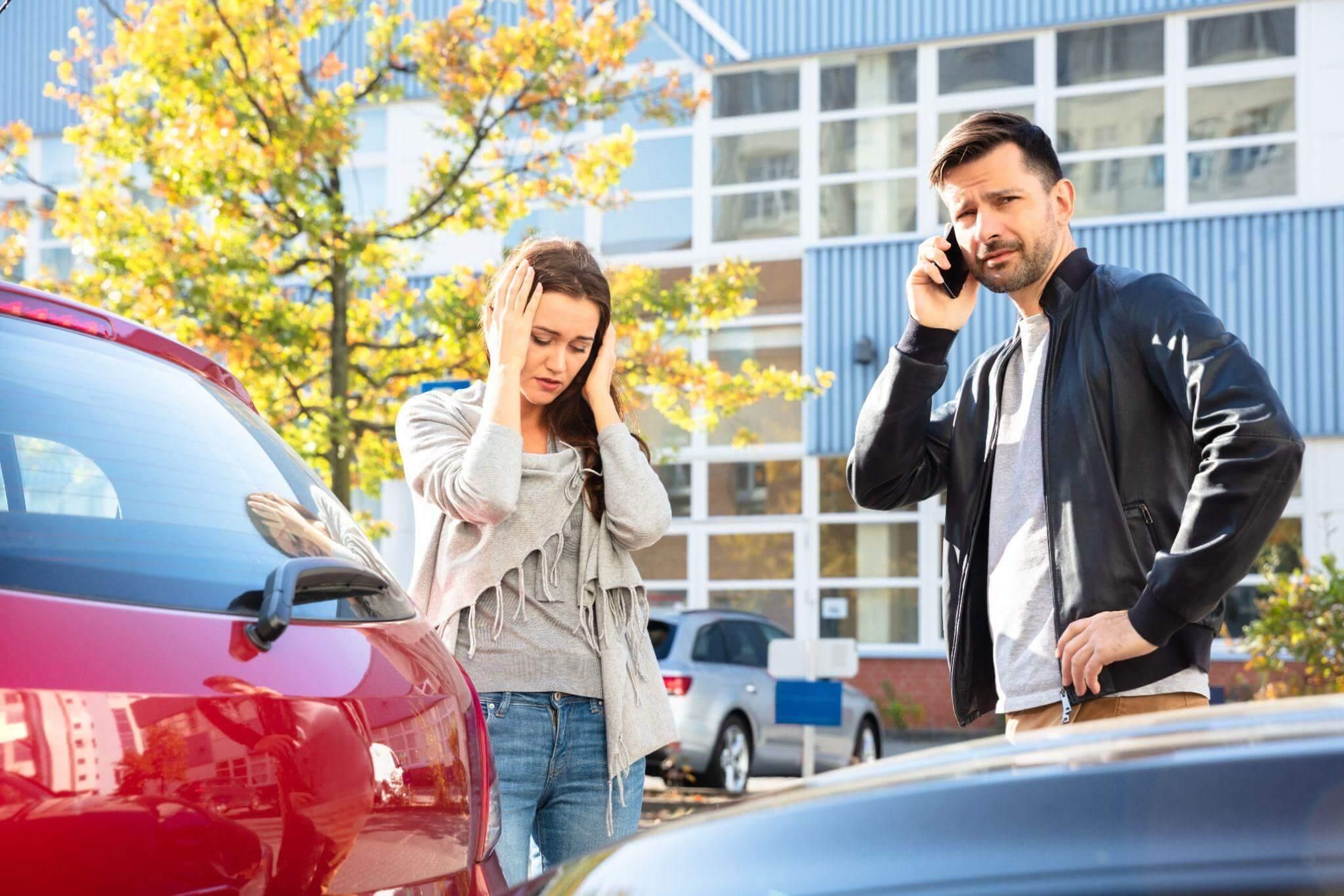 a man and a woman standing next to a car talking on a cell phone