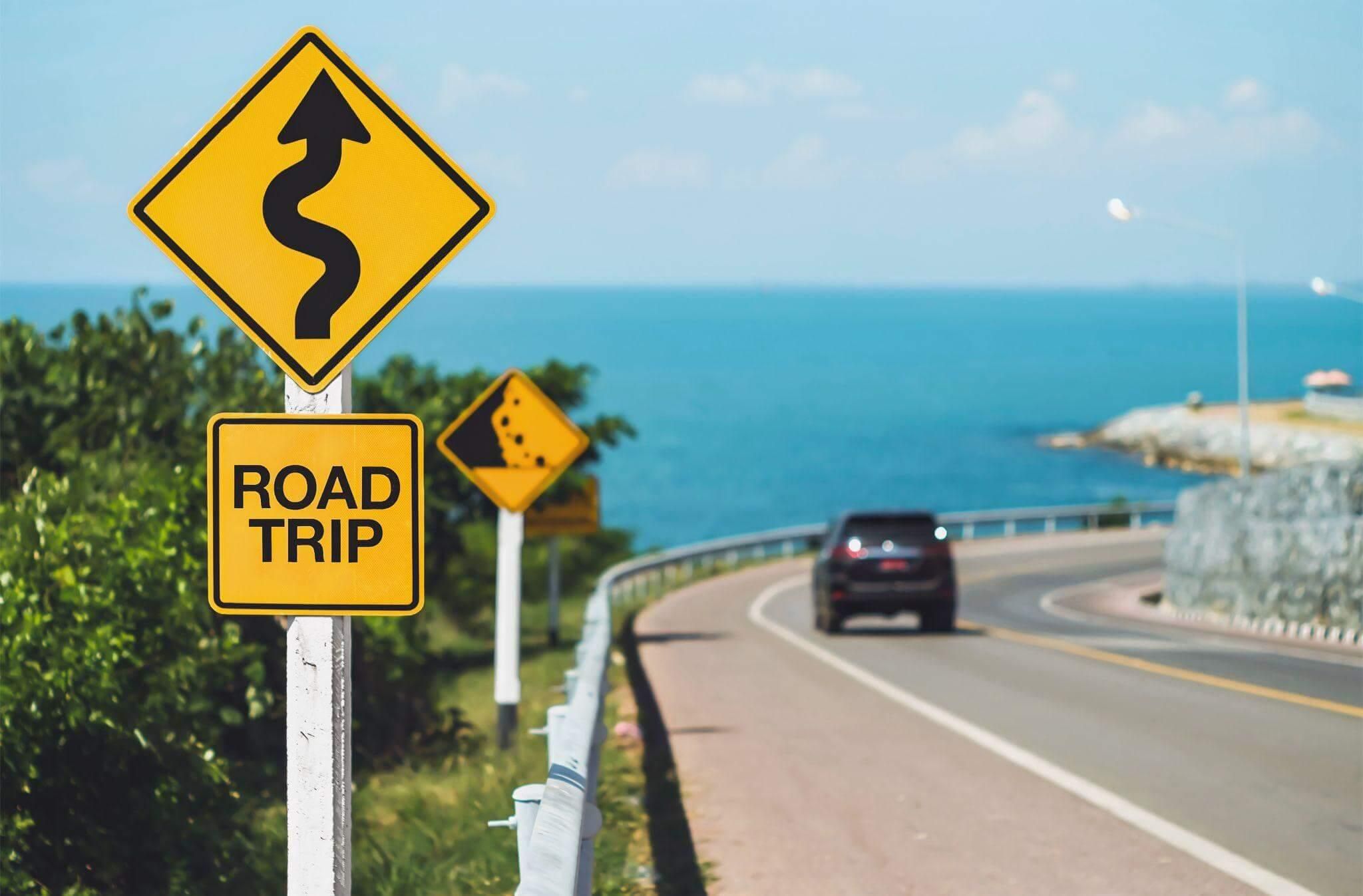 a road sign on the side of a road next to the ocean