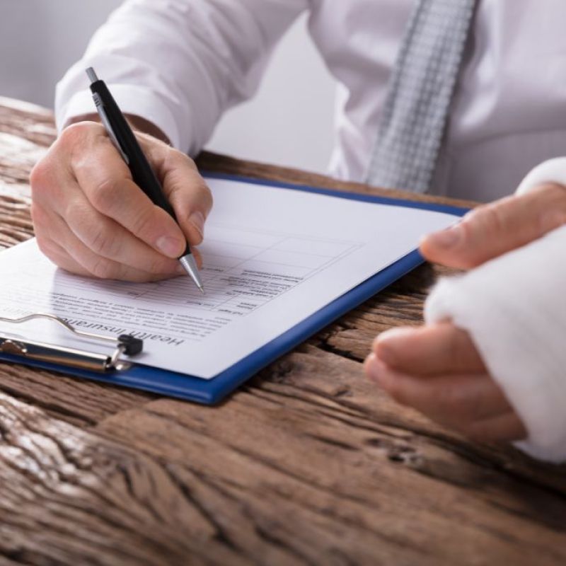 man wearing a cast on his arm signing a paper