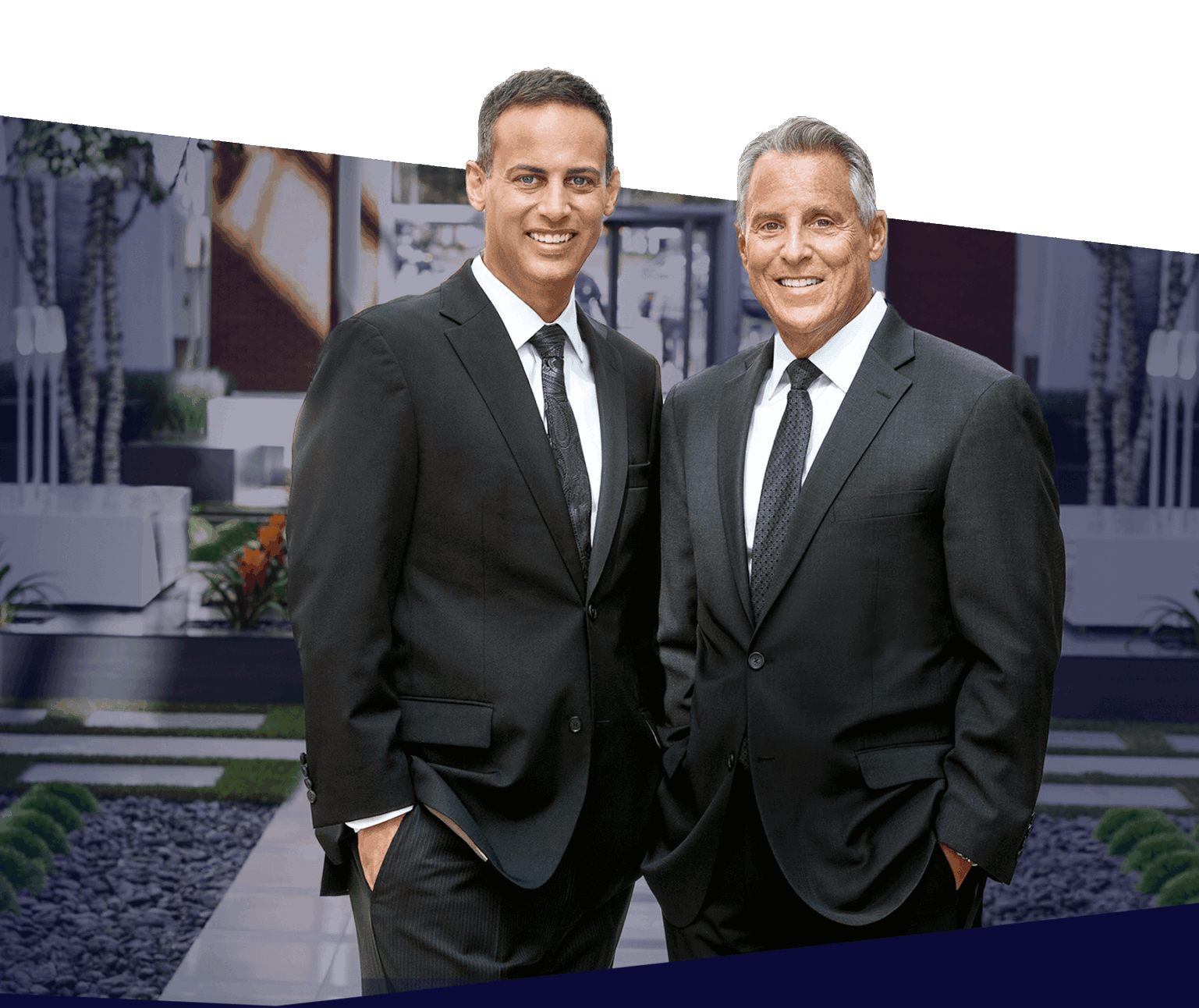 Two men in suits smiling outdoors, standing in a landscaped garden with modern design elements.