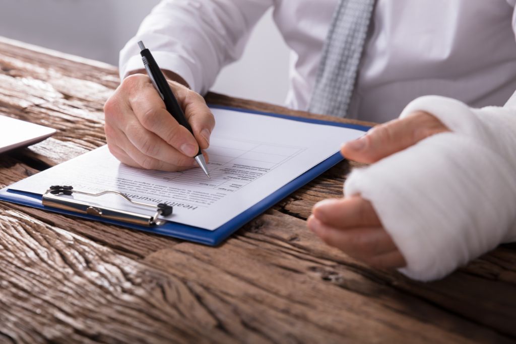 man wearing a cast on his arm signing a paper