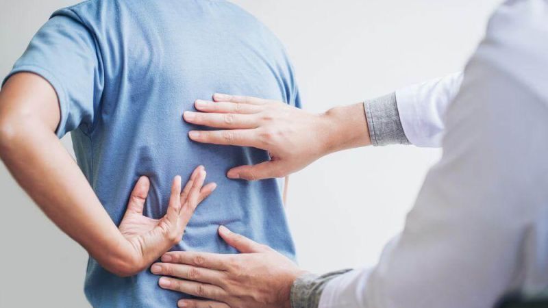 Man holding his back in pain while considering chiropractic