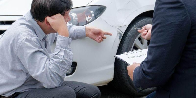 Man sitting by a white car, possibly