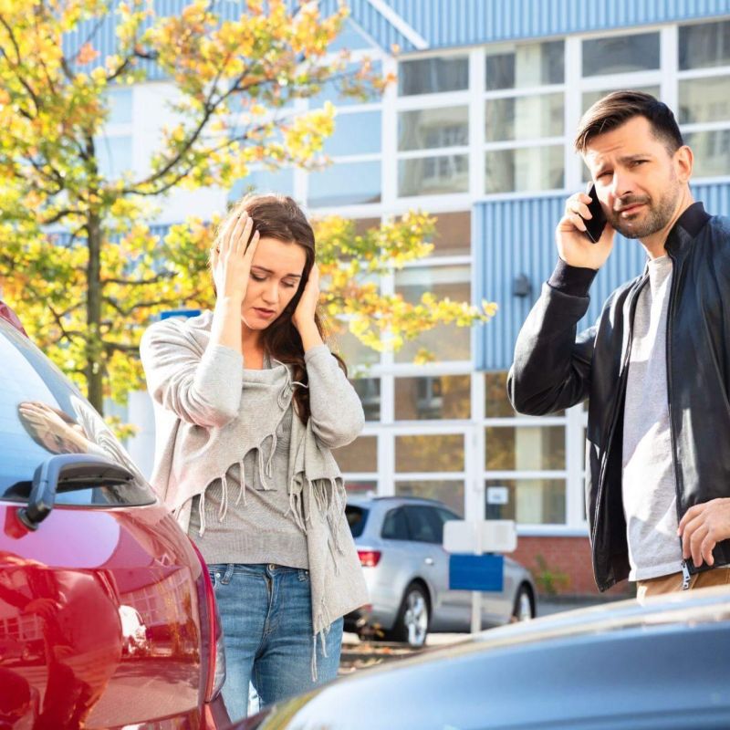 a man and a woman standing next to a car talking on a cell phone