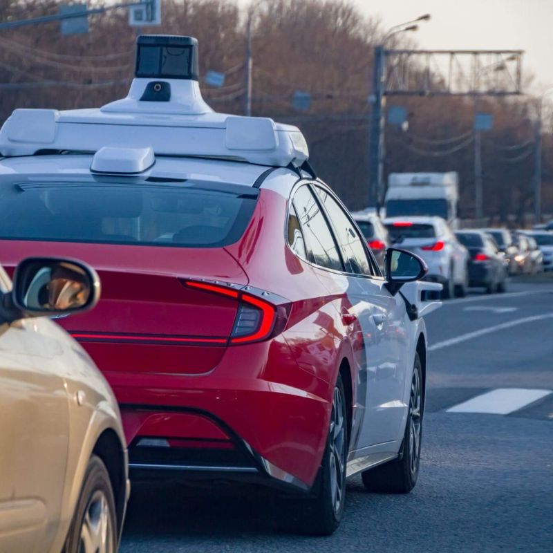 Self-driving red car by traffic light on city street