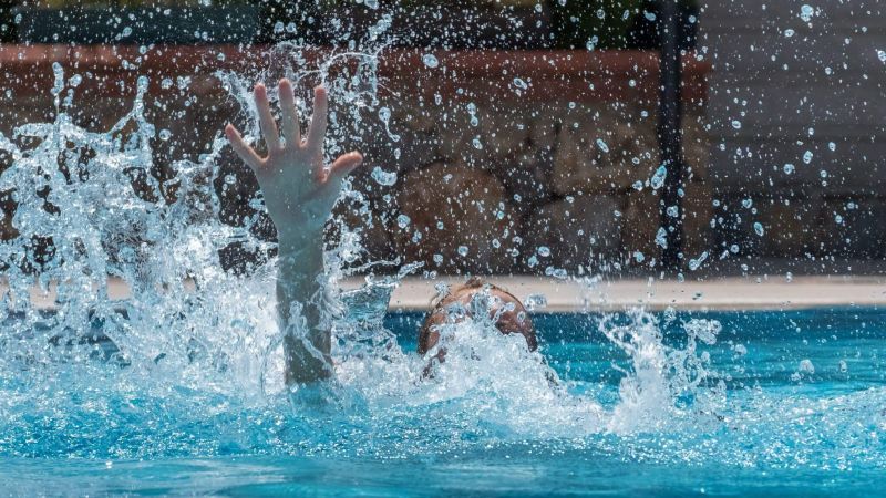 a person splashing water in a swimming pool and that person seems to be drowning