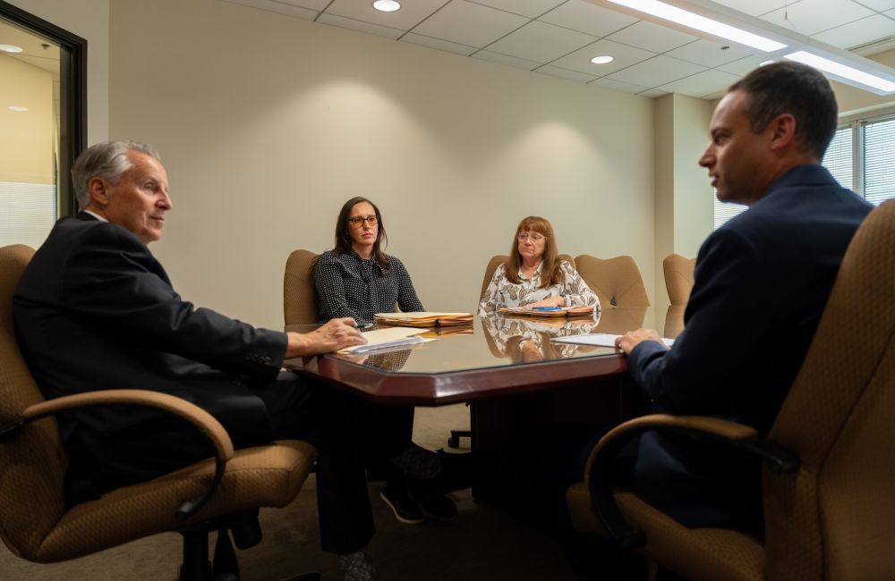 Business professionals in a meeting room discussing documents around a conference table.