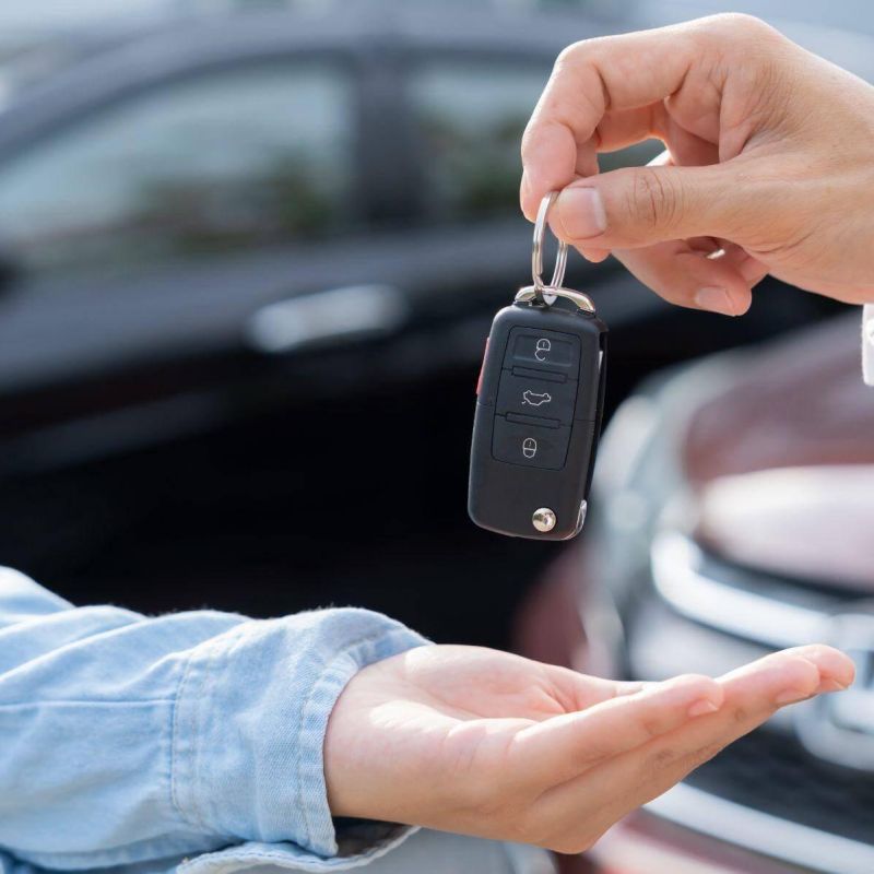a person handing a car key to another person in what appears to be a dealership