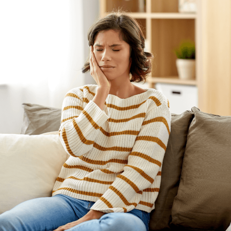 Woman holding her jaw due to TMJ pain