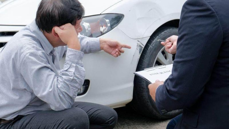 Man sitting by a white car, possibly