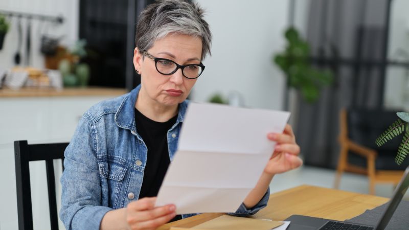 Woman looking upset at benefit paperwork
