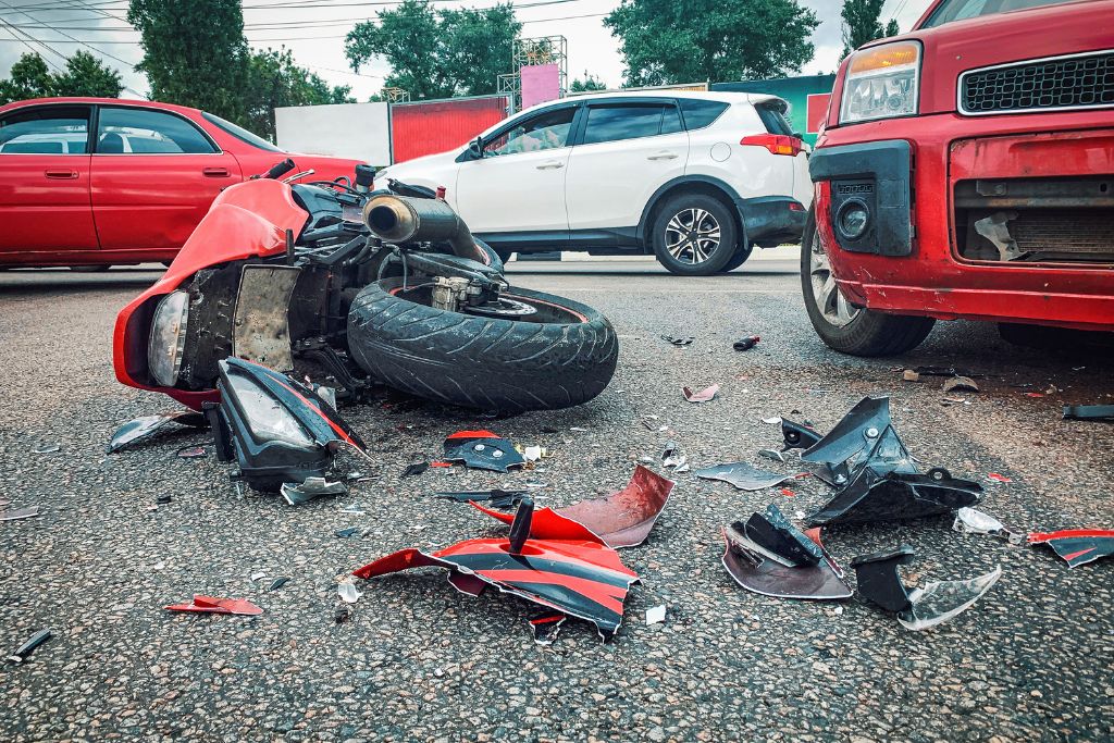 red motorcycle on the ground after an accident involving a truck