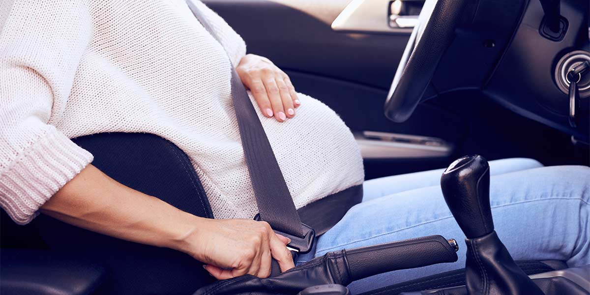 pregnant woman putting a seatbelt on 
