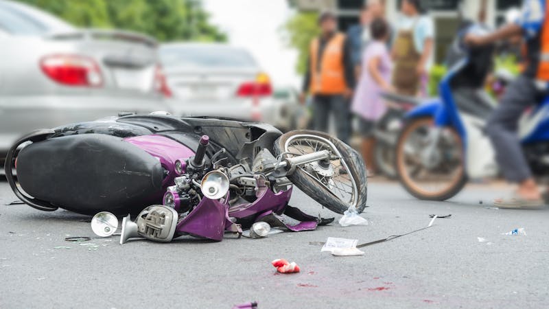 | Matz Injury Law Crashed motorcycle on city street surrounded by onlookers, highlighting road safety and accident scene.