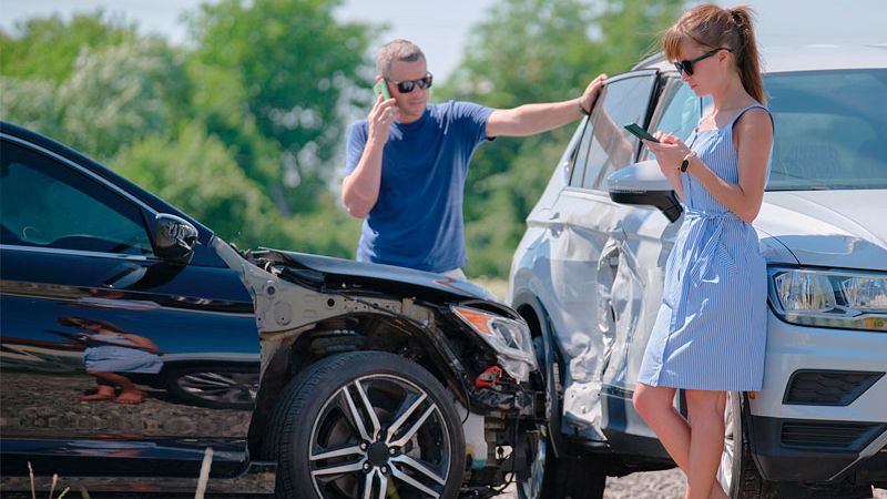 | Matz Injury Law A man and a woman standing outside their vehicles after an auto accident