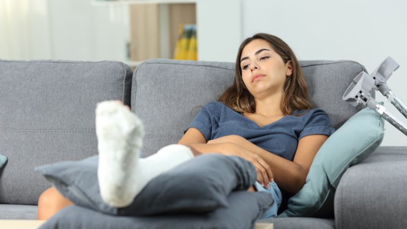 top attorneys | Matz Injury Law Woman sitting on the couch with a foot cast on