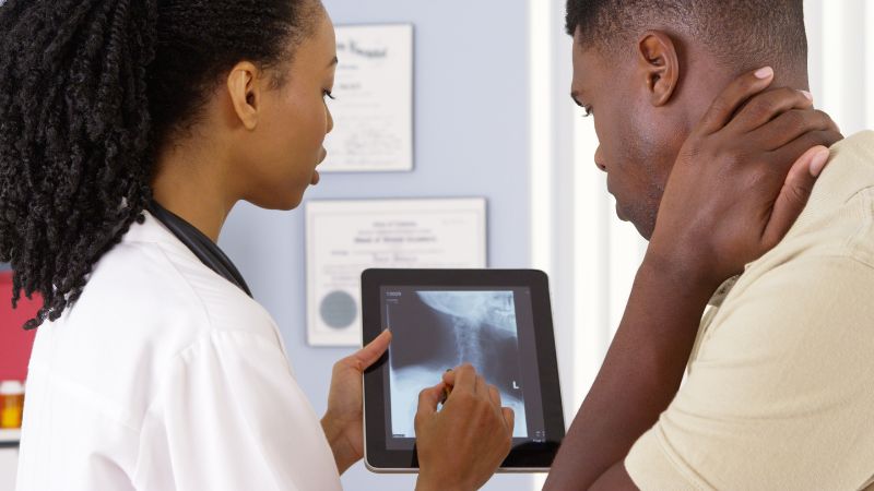 doctor showing a patient a neck x ray image of their injury