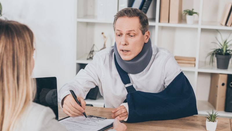 | Matz Injury Law man wearing a neck and arm brace signing paperwork