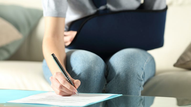 woman with injured arm filling out paperwork after car accident