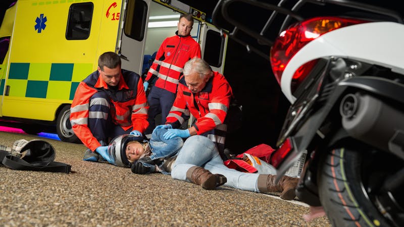 | Matz Injury Law Emergency responders aid an injured motorcyclist at night beside an ambulance.
