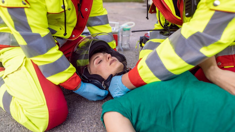 | Matz Injury Law Emergency responders assist an injured person on the ground, ensuring their head is stabilized with caution.