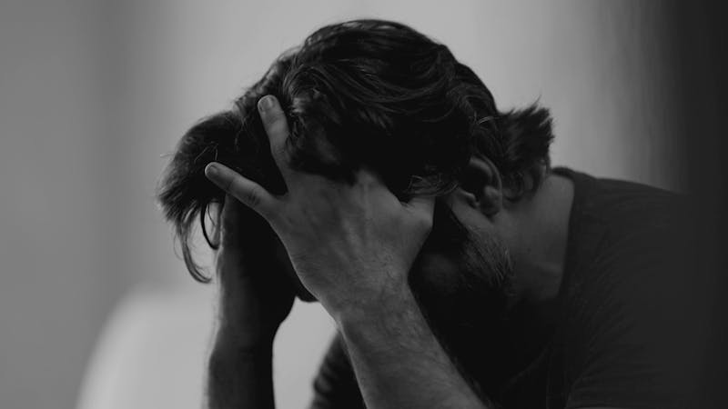 | Matz Injury Law A man sits with his head in his hands, displaying distress. The background is softly blurred, adding to the somber atmosphere of the scene.